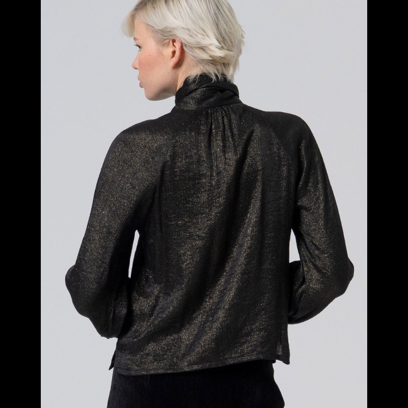 Blusa preta com brilho dourado, de decote em V com laço no colarinho. Blusa de manga comprida a terminar com apliques em preto e dourado no punho.
Composição: 65%Viscose + 35%Poliamida
