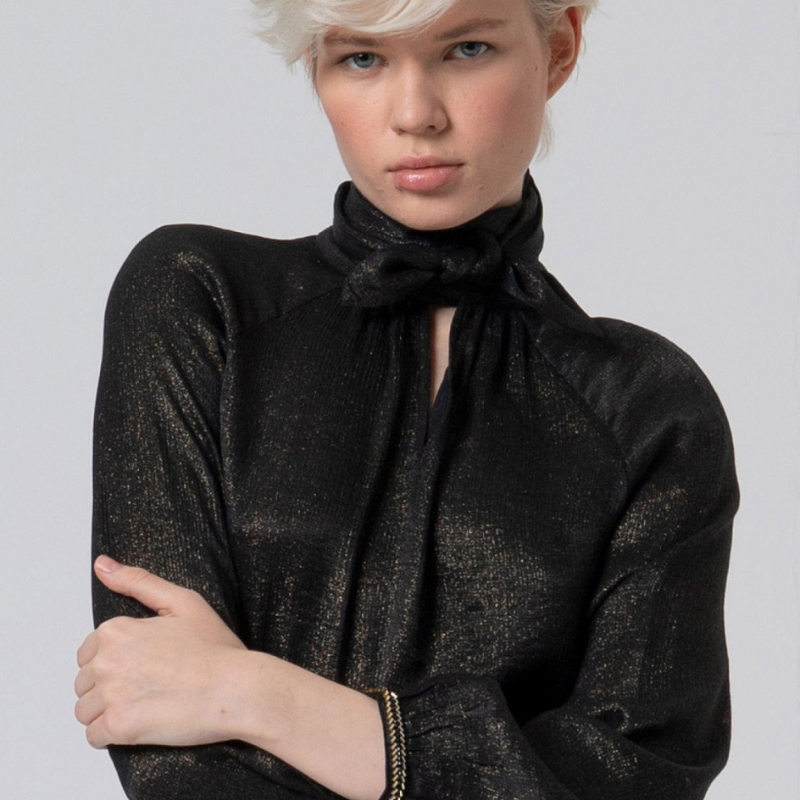 Blusa preta com brilho dourado, de decote em V com laço no colarinho. Blusa de manga comprida a terminar com apliques em preto e dourado no punho.
Composição: 65%Viscose + 35%Poliamida