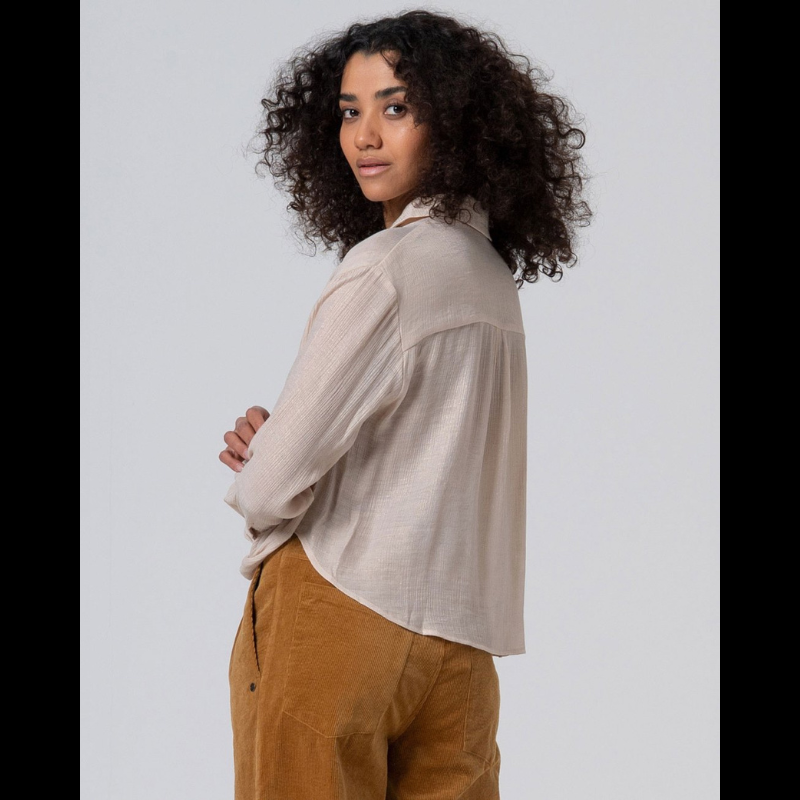 Camisa de decote em V, com bainha drapeada na frente, na cor crú com brilho dourado.
Composição: 65%Visose + 35%Poliamida