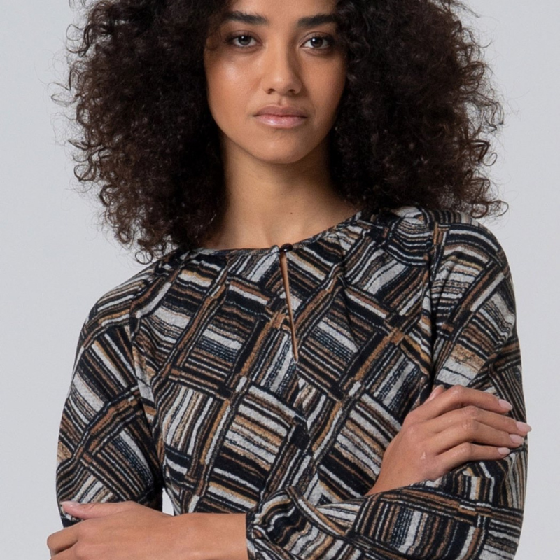 Camisola solta com padrão geométrico em tons preto, cinza e castanho. Decote redondo a fechar com um botão e deixar uma abertura em gota. Camisola de manga comprida a terminar em elástico.
Composição: 50%Poliéster reciclado + 45%Poliéster + 5%Elastano