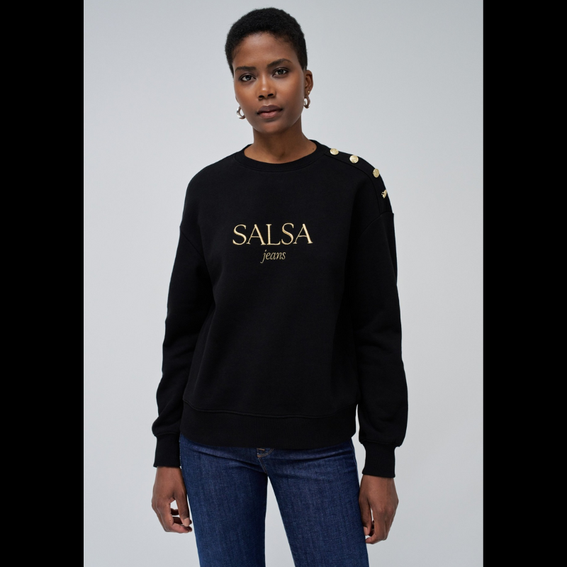 Camisola de felpa em preto com branding em dourado. Camisola de mangas compridas com punhos canelados e decote redondo. Detalhe de quatro botões dourados num ombro.
Corte: Regular fit