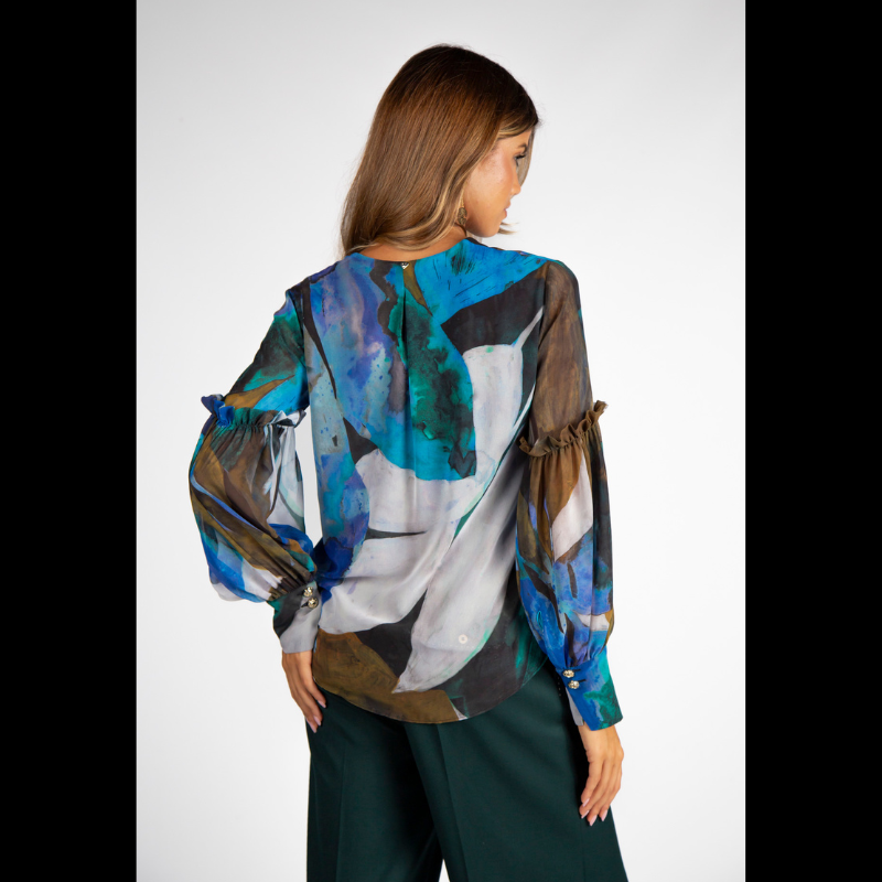 Túnica de decote em V com estampado abstrato em tons de turquesa, azul e verde. Túnica de mangas compridas em formato balão, levemente transparentes e forrada no corpo. Mangas a terminar com punho alto com dois botões metálicos em relevo.
Composição: 100%Poliester