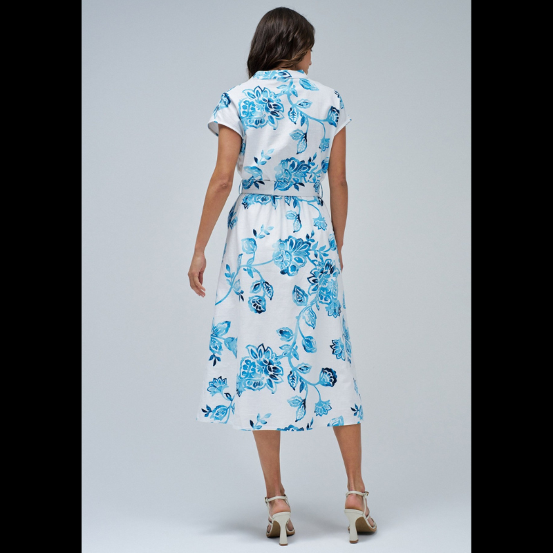 Vestido camiseiro branco com estampa floral em tons azuis. Vestido midi com decote em V e com abertura na frente com botões em madeira até à cintura. Vestido com corte na cintura com elástico e a terminar com racha frontal. Vestido de mangas cavas com bolsos laterias e com cinto removível com fivela em ráfia.
Composição: 100% Algodão