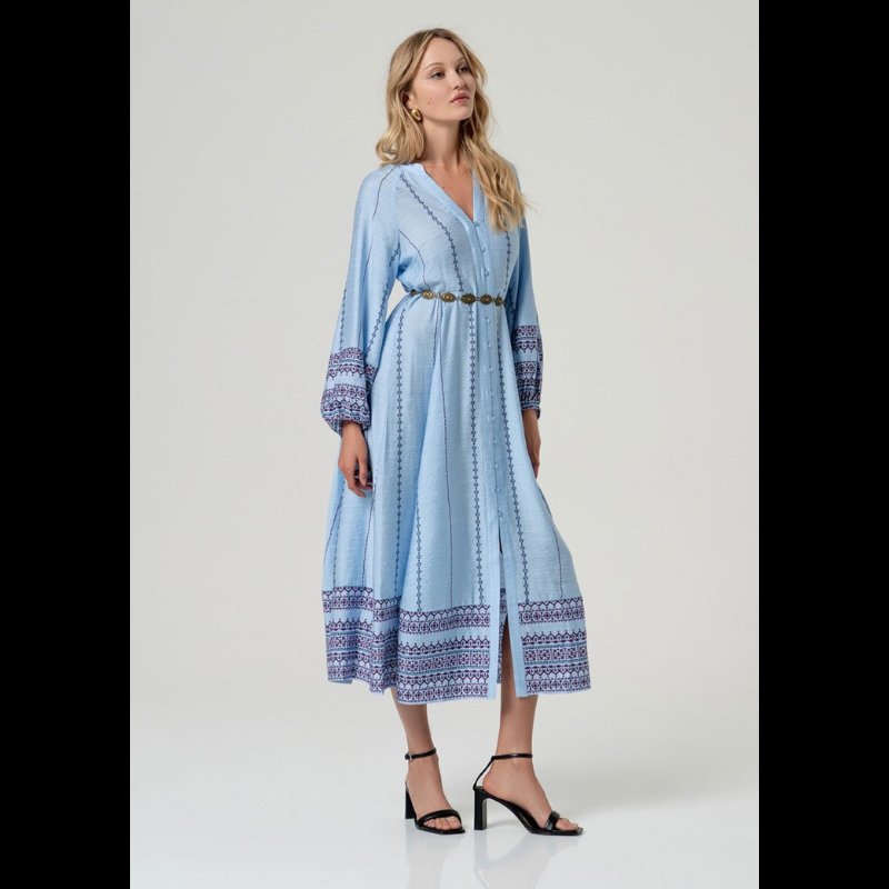 Vestido camiseiro midi em azul com cintura marcada e decote em V elegante. Mangas compridas com elástico nos punhos e detalhes de bordado geométrico em marinho e bordô. Faixa bordada na barra e nos punhos adiciona sofisticação. Fecha na frente com botões em azul claro e vem acompanhado por um cinto do mesmo tecido e padrão. Peça versátil perfeita para o dia a dia com um toque de refinamento.