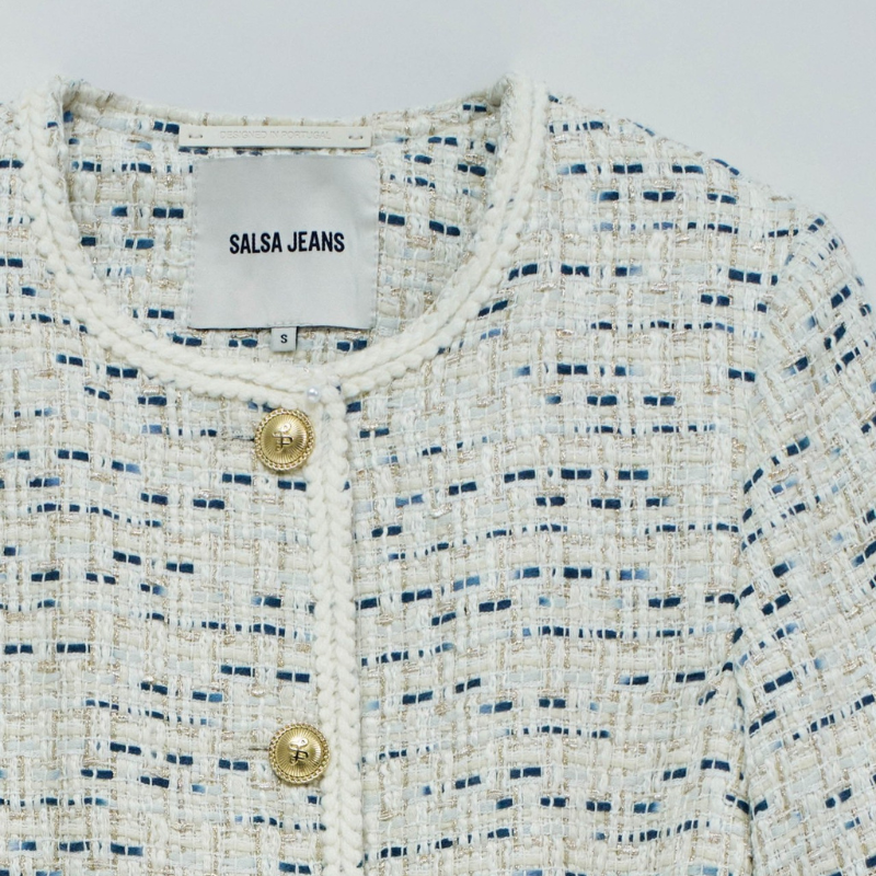 Casaco Tweed cintado em crú com contrastes em tons azuis e fios de lurex em dourado. Casaco de mangas compridas e decote redondo a fechar na frente com botões dourados com detalhe de branding e cinto em cordão. Dois bolsos frontais abertos e de chapa com detalhe de botão em dourado.