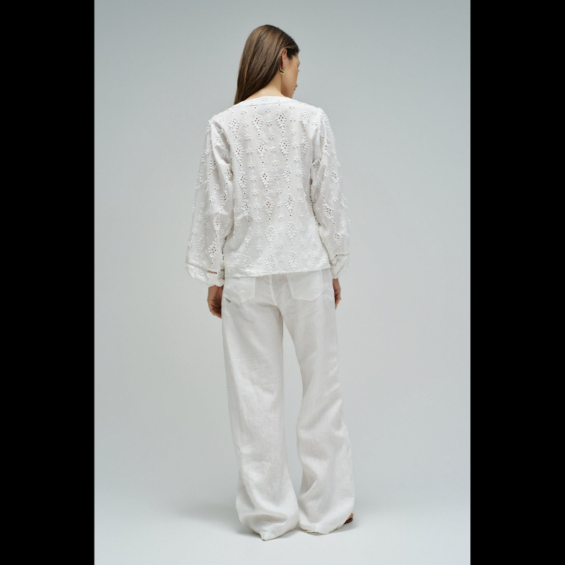 Blusa em branco com bordado em relevo e apliques florais tridimensionais que conferem textura e movimento à peça. Decote em V elegante e abertura frontal com botões para fácil ajuste. Mangas abalonadas que criam um efeito volumoso e feminino, complementadas por punhos com elástico para um acabamento confortável. Fit regular que se adapta perfeitamente ao corpo. Uma peça versátil ideal para criar looks sofisticados do dia a dia ou ocasiões especiais.