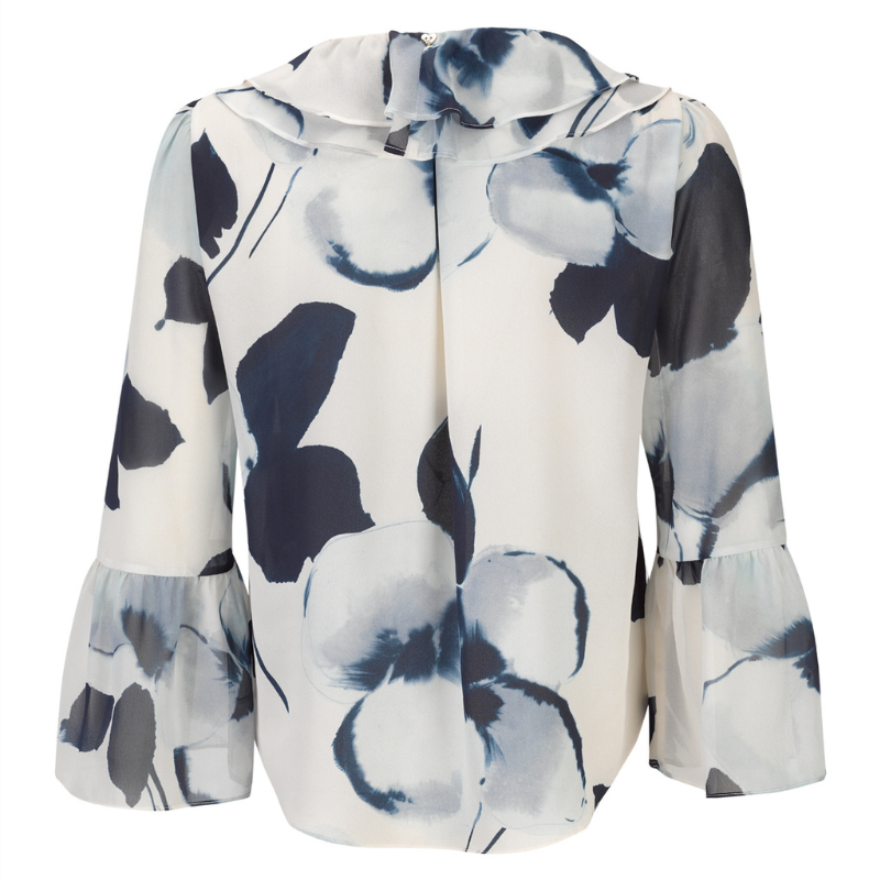 Blusa com estampado floral abstrato com padrão, em tons de azul-marinho, azul-claro e branco, confere um efeito delicado e atual ao visual. A gola com folhos traz um toque romântico, enquanto o laço azul escuro amovível no decote permite adaptar o look conforme a ocasião. Fecho frontal por botões prata e mangas compridas com punhos em folho que completam o design com requinte e feminilidade.
