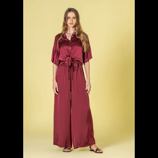 Blusa em tecido acetinado, em bordeaux, com acabamento sofisticado e confortável. Modelo oversize que oferece liberdade de movimento e um visual descontraído e elegante. Decote redondo clássico que combina com qualquer estilo. Mangas curtas com detalhe em folho, adicionando um toque feminino e delicado ao design. Fechamento frontal com botões funcionais, permitindo ajuste perfeito ao corpo. Peça versátil ideal para looks do dia a dia ou ocasiões mais descontraídas.