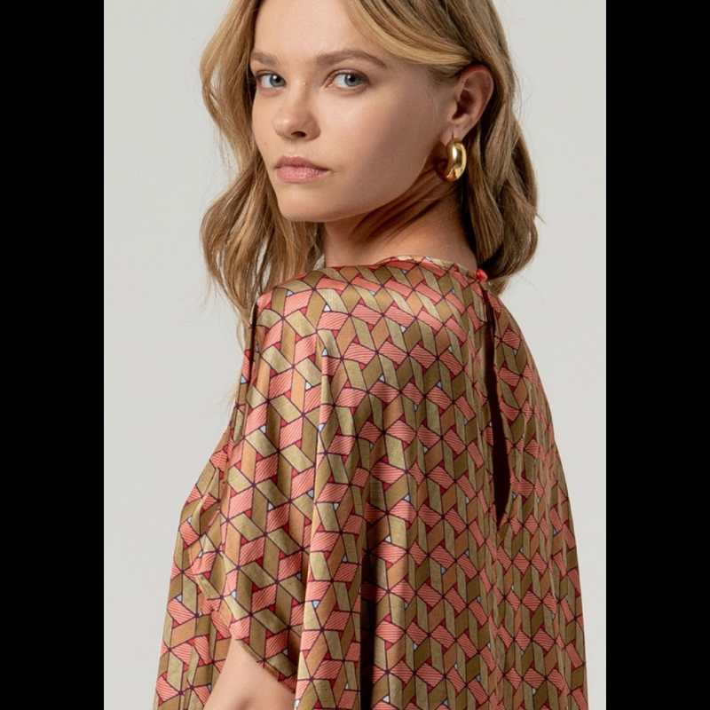 Esta blusa capa SURKANA apresenta um design refinado em acetinado com motivos geométricos vibrantes que combinam vermelho e múltiplas tonalidades. O decote circular e silhueta oversize oferecem liberdade de movimento e elegância atemporal, enquanto o fecho traseiro com botão garante um ajuste seguro e discreto. Uma escolha sofisticada para quem valoriza qualidade e estilo.