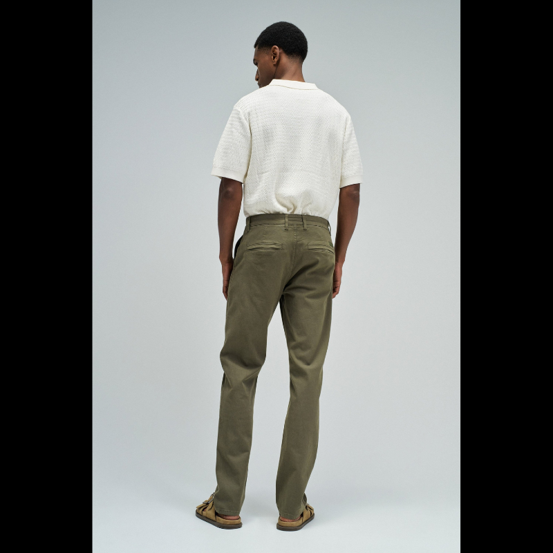 Calça chino em verde com cintura média e corte slim que combina estilo e conforto. Apresenta quatro bolsos funcionais, presilhas para cinto e abertura prática com fecho de correr e botão. Peça versátil ideal para o dia a dia, oferecendo um visual moderno e bem ajustado.