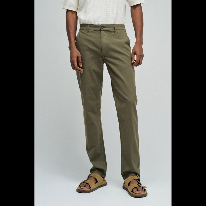 Calça chino em verde com cintura média e corte slim que combina estilo e conforto. Apresenta quatro bolsos funcionais, presilhas para cinto e abertura prática com fecho de correr e botão. Peça versátil ideal para o dia a dia, oferecendo um visual moderno e bem ajustado.