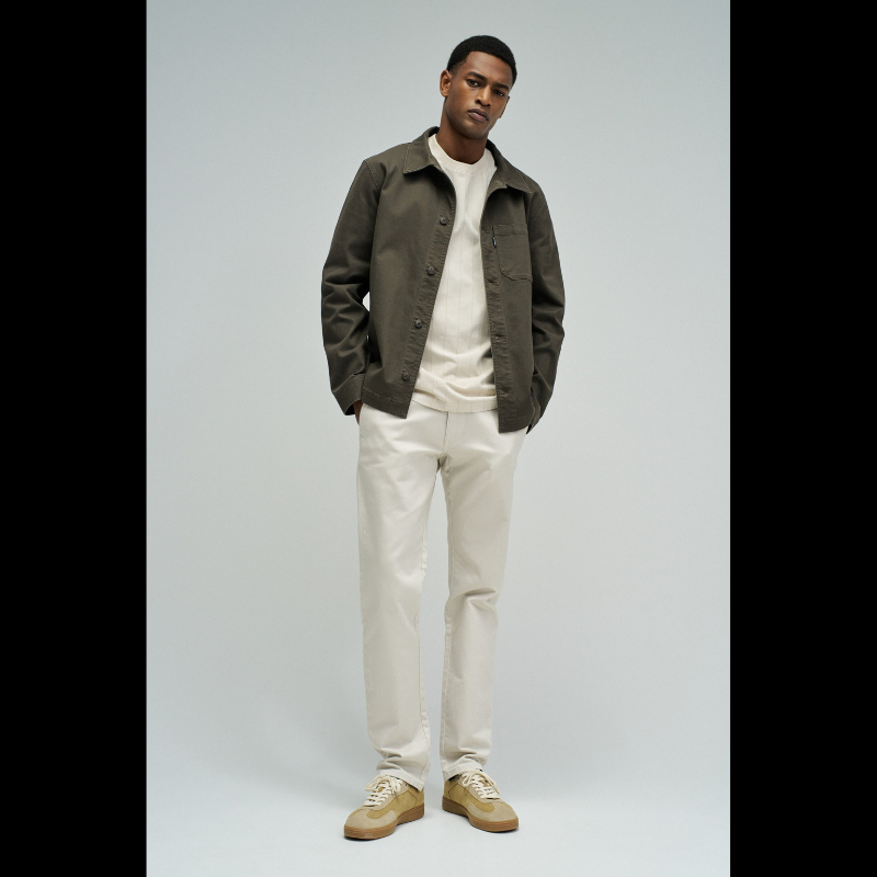 Calças chino de corte slim fit que combinam estilo e conforto. Confecionadas em tom cru neutro, apresentam cintura média com cordão interno ajustável para um encaixe personalizado. O design inclui quatro bolsos funcionais e presilhas, garantindo versatilidade no dia a dia. Ideais para criar looks casual refinados ou composições mais formais, estas calças adaptam-se facilmente a diferentes ocasiões e estilos pessoais.