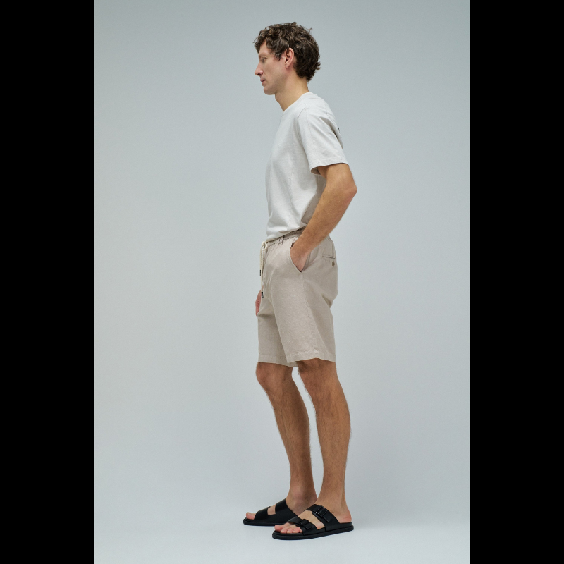 Calções em linho com um toque de sofisticação casual. O corte regular e a cintura média proporcionam conforto e elegância, enquanto o fecho de correr e botão garantem segurança. O cordão ajustável permite um ajuste personalizado conforme necessário. Quatro bolsos funcionais e presilhas completam o design prático. A cor bege neutra combina facilmente com qualquer peça do seu guarda-roupa, tornando estes calções uma escolha versátil para dias quentes.