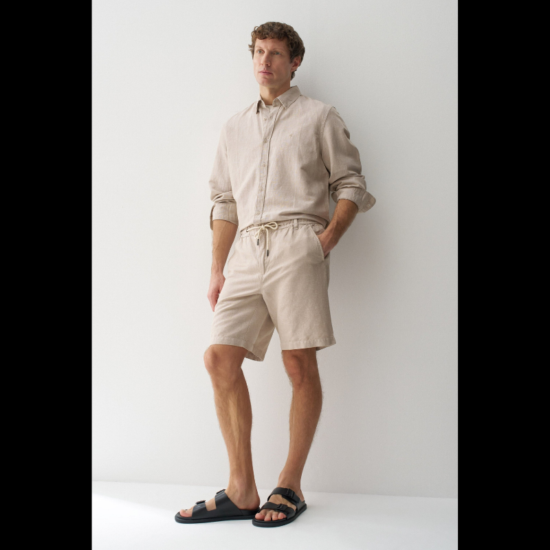 Calções em linho com um toque de sofisticação casual. O corte regular e a cintura média proporcionam conforto e elegância, enquanto o fecho de correr e botão garantem segurança. O cordão ajustável permite um ajuste personalizado conforme necessário. Quatro bolsos funcionais e presilhas completam o design prático. A cor bege neutra combina facilmente com qualquer peça do seu guarda-roupa, tornando estes calções uma escolha versátil para dias quentes.