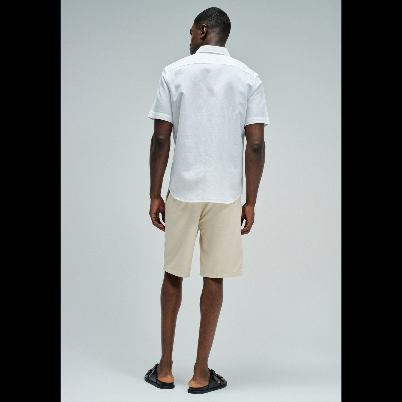 Camisa de manga curta em linho, perfeita para os dias quentes. Cor branco puro com fit regular que se adapta confortavelmente ao corpo. Apresenta decote clássico com colarinho, abertura frontal com botões funcionais e bolso prático no peito. O linho garante respirabilidade e um toque natural, ideal para criar looks casual e sofisticados. Uma peça versátil que combina com calças, shorts ou saias para qualquer ocasião.
