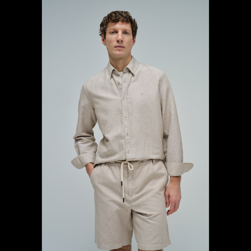Camisa de linho em tom bege que combina conforto e elegância. Corte regular que se adapta perfeitamente ao corpo, com decote de colarinho clássico e mangas compridas. Abertura frontal com botões para um visual versátil e fácil de usar. Ideal para criar looks sofisticados tanto no dia a dia como em ocasiões mais formais. A mistura de linho garante respirabilidade e um toque natural que envelhece com estilo.
