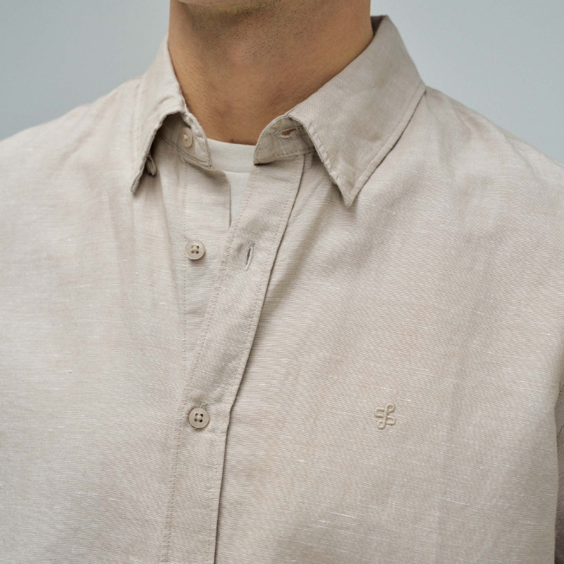 Camisa de linho em tom bege que combina conforto e elegância. Corte regular que se adapta perfeitamente ao corpo, com decote de colarinho clássico e mangas compridas. Abertura frontal com botões para um visual versátil e fácil de usar. Ideal para criar looks sofisticados tanto no dia a dia como em ocasiões mais formais. A mistura de linho garante respirabilidade e um toque natural que envelhece com estilo.