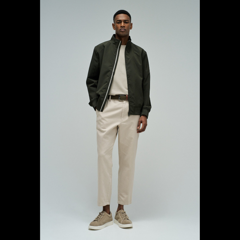 Casaco bomber em verde escuro com design versátil e funcional. Apresenta abertura frontal com fecho de correr para ajuste fácil, fit regular que se adapta confortavelmente ao corpo, e mangas compridas com punhos elásticos que garantem um acabamento limpo. Equipado com dois bolsos laterais práticos e bolso interior com fecho para maior segurança dos seus pertences. O elástico na cintura proporciona um corte definido e moderno. Uma peça essencial do guarda-roupa que combina estilo casual com funcionalidade.