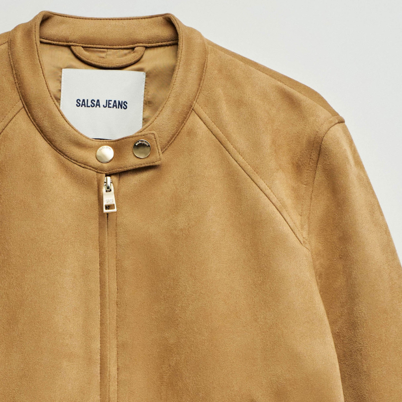 Casaco em suede camel com corte slim fit que combina elegância e conforto. Apresenta mangas compridas com fecho nos punhos para um ajuste preciso, abertura frontal com fecho de correr e decote redondo realçado por dois botões dourados de mola. Dois bolsos funcionais com fecho garantem segurança aos seus pertences. Uma peça versátil que se adapta a diversos estilos, ideal para criar looks sofisticados em qualquer estação.
