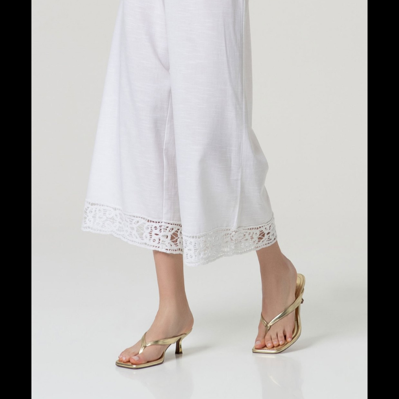 Calça flare em branco que combina elegância e conforto. Cintura alta com fecho de lado e colcheta, complementada por elástico na parte traseira para um ajuste perfeito. A barra apresenta um delicado detalhe de bordados abertos que confere um toque sofisticado ao design. Confecionada em viscose e algodão, oferece leveza e respirabilidade ideais para o dia a dia. Uma peça versátil que se adapta a diversos estilos e ocasiões.