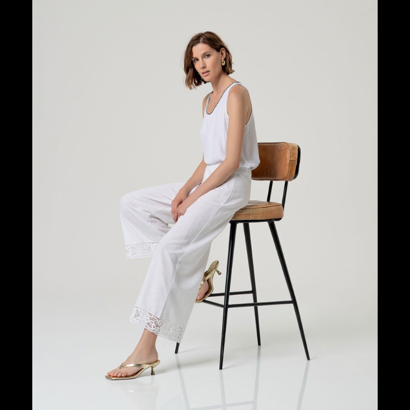 Calça flare em branco que combina elegância e conforto. Cintura alta com fecho de lado e colcheta, complementada por elástico na parte traseira para um ajuste perfeito. A barra apresenta um delicado detalhe de bordados abertos que confere um toque sofisticado ao design. Confecionada em viscose e algodão, oferece leveza e respirabilidade ideais para o dia a dia. Uma peça versátil que se adapta a diversos estilos e ocasiões.