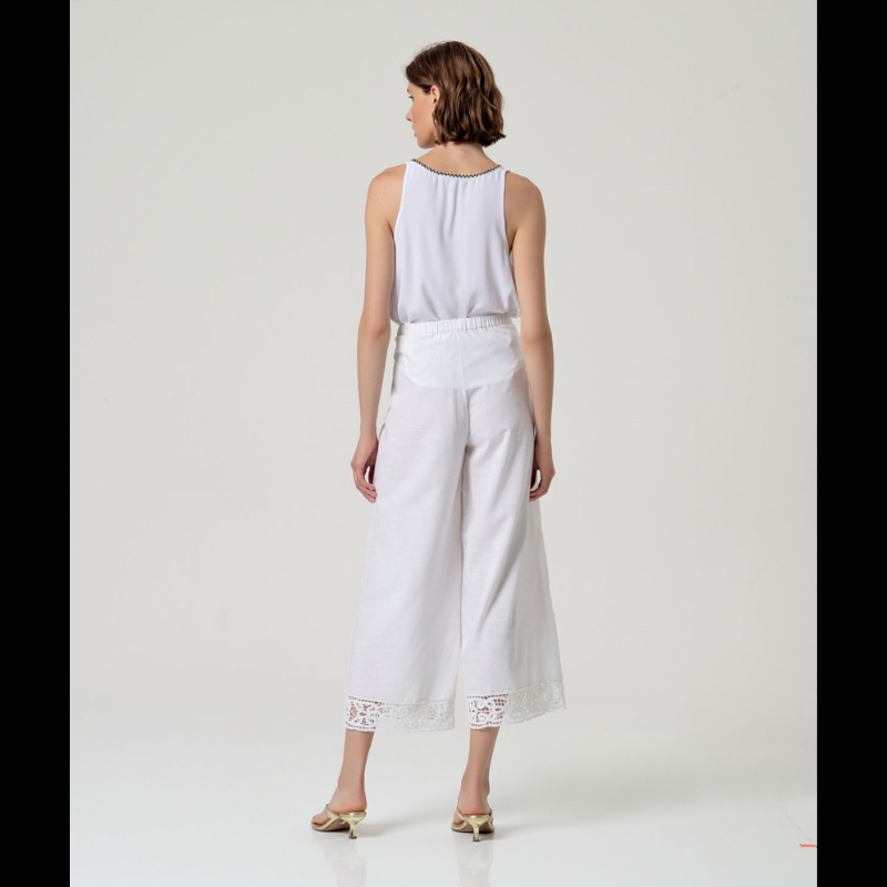 Calça flare em branco que combina elegância e conforto. Cintura alta com fecho de lado e colcheta, complementada por elástico na parte traseira para um ajuste perfeito. A barra apresenta um delicado detalhe de bordados abertos que confere um toque sofisticado ao design. Confecionada em viscose e algodão, oferece leveza e respirabilidade ideais para o dia a dia. Uma peça versátil que se adapta a diversos estilos e ocasiões.