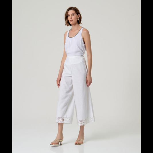 Calça flare em branco que combina elegância e conforto. Cintura alta com fecho de lado e colcheta, complementada por elástico na parte traseira para um ajuste perfeito. A barra apresenta um delicado detalhe de bordados abertos que confere um toque sofisticado ao design. Confecionada em viscose e algodão, oferece leveza e respirabilidade ideais para o dia a dia. Uma peça versátil que se adapta a diversos estilos e ocasiões.