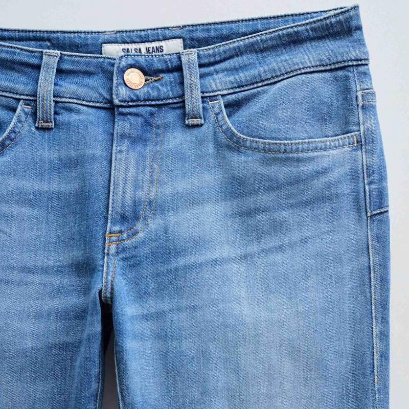 Calças jeans wonder de cintura baixa e efeito "push up" com detalhes de bolsos traseiros com botões. Calças de cinco bolsos e presilhas na cintura com perna a terminar à boca de sino. Abertura com fecho de correr e um botão.