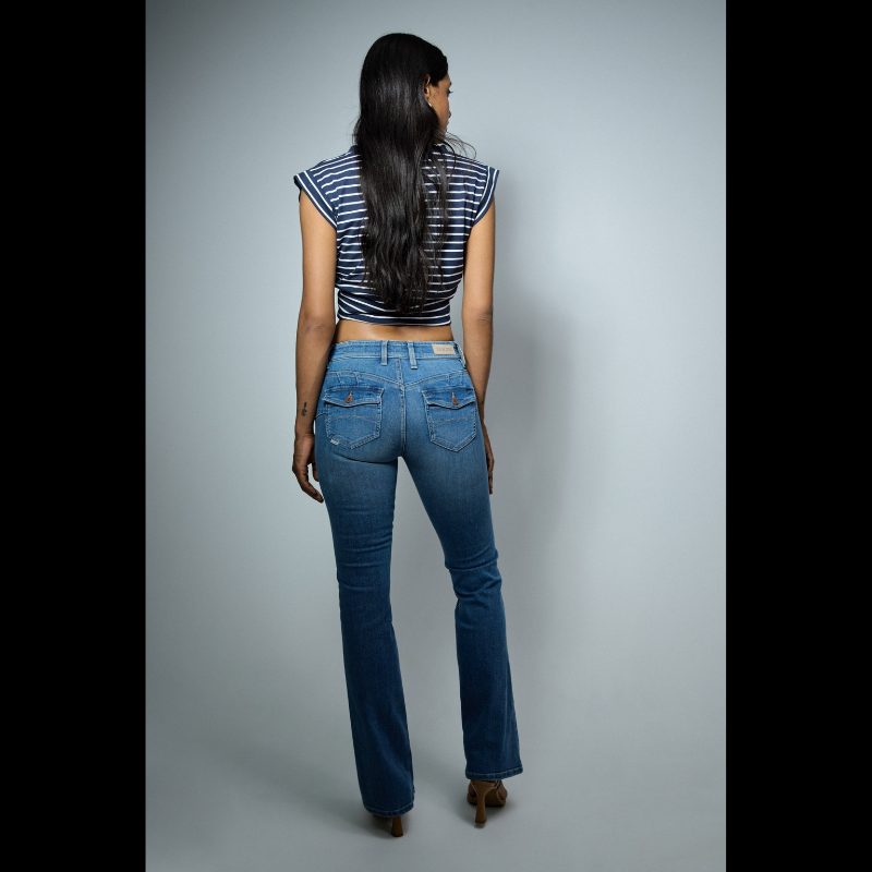 Calças jeans wonder de cintura baixa e efeito "push up" com detalhes de bolsos traseiros com botões. Calças de cinco bolsos e presilhas na cintura com perna a terminar à boca de sino. Abertura com fecho de correr e um botão.