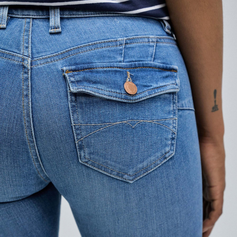 Calças jeans wonder de cintura baixa e efeito "push up" com detalhes de bolsos traseiros com botões. Calças de cinco bolsos e presilhas na cintura com perna a terminar à boca de sino. Abertura com fecho de correr e um botão.