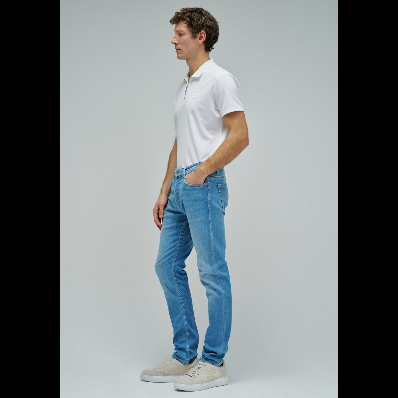 Calças jeans slim fit em azul claro com cintura média e perna ajustada. Apresenta abertura com botões, cinco bolsos funcionais e presilhas para cinto. Corte moderno que realça a silhueta, ideal para um visual casual e versátil no dia a dia.