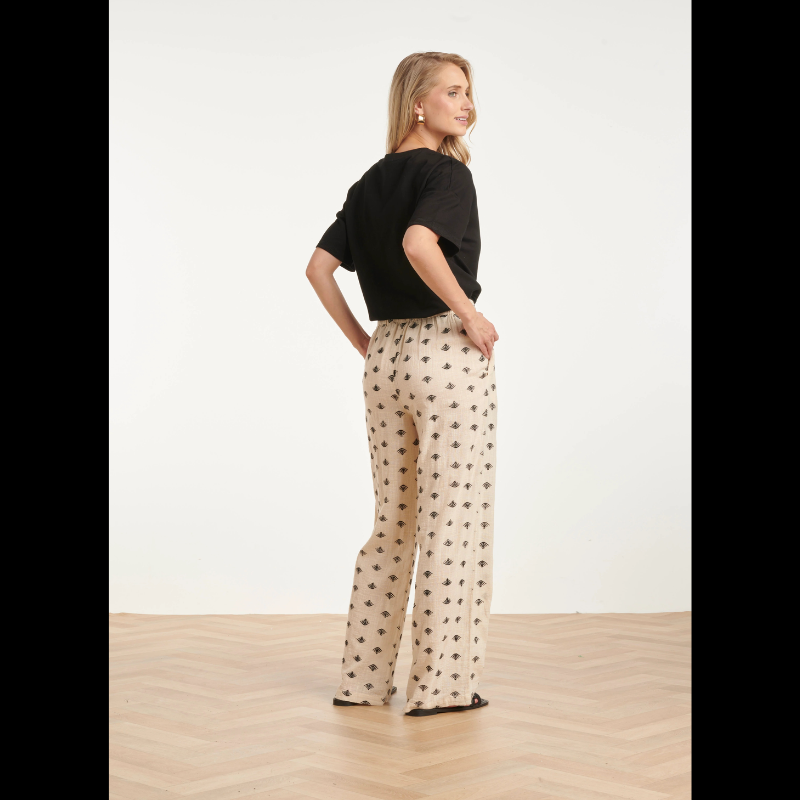 Calças beges Wide Leg com estampado Azteca em preto e castanho. Calças com bolsos nas laterais e cintura com elástico na parte de trás.