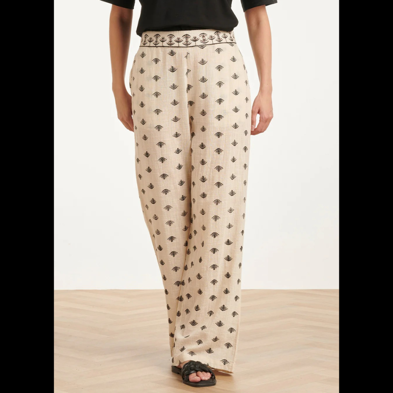 Calças beges Wide Leg com estampado Azteca em preto e castanho. Calças com bolsos nas laterais e cintura com elástico na parte de trás.
