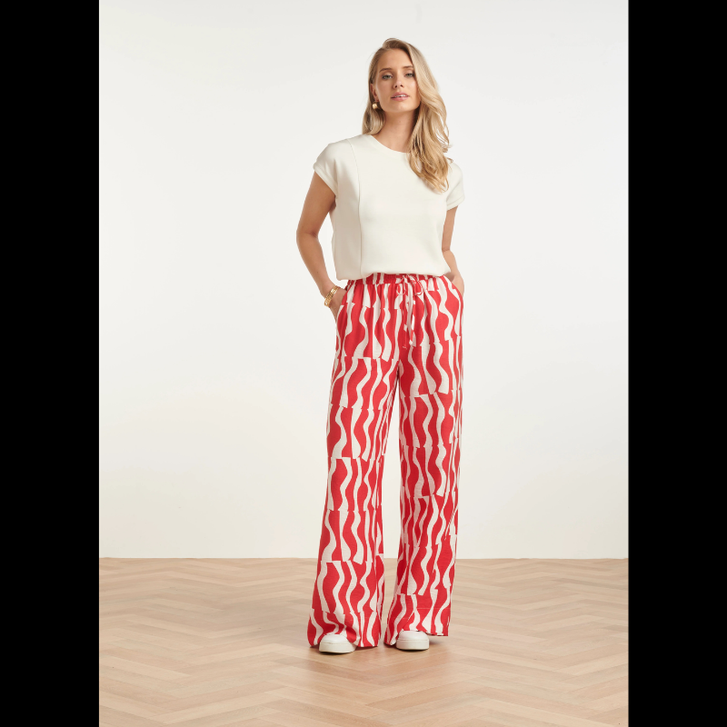 Calças largas com estampa ondulada em vermelho e branco que combinam conforto e estilo. Cintura elástica com atilho ajustável para um encaixe perfeito. Bolsos funcionais para praticidade do dia a dia. Peça versátil que funciona tanto em looks casuais como em composições mais descontraídas.
