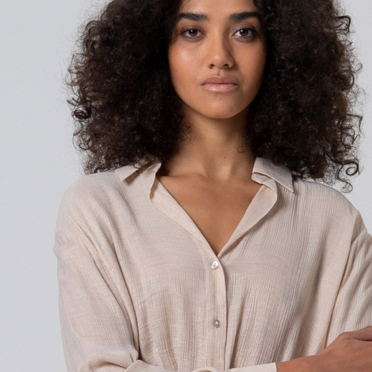 Camisa de decote em V, com bainha drapeada na frente, na cor crú com brilho dourado.
Composição: 65%Visose + 35%Poliamida