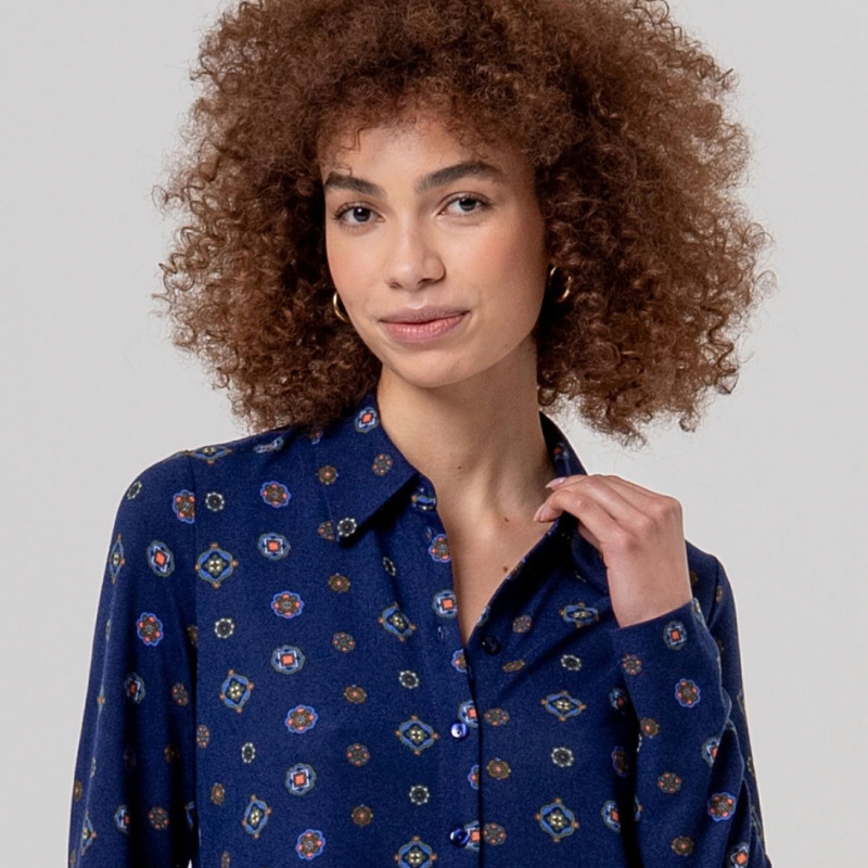 Camisa clássica em azul-marinho com gola e mangas longas, botões azuis e tecido fluido de queda suave. Estampa foulard com medalhões geométricos pequenos que transmitem elegância e sofisticação cosmopolita.
