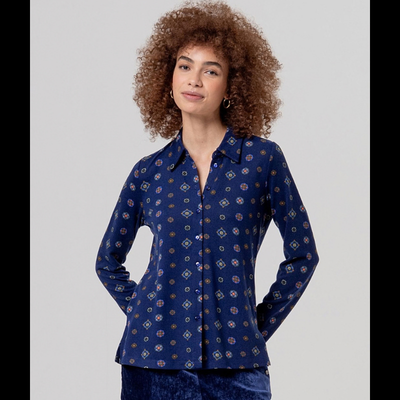 Camisa clássica em azul-marinho com gola e mangas longas, botões azuis e tecido fluido de queda suave. Estampa foulard com medalhões geométricos pequenos que transmitem elegância e sofisticação cosmopolita.