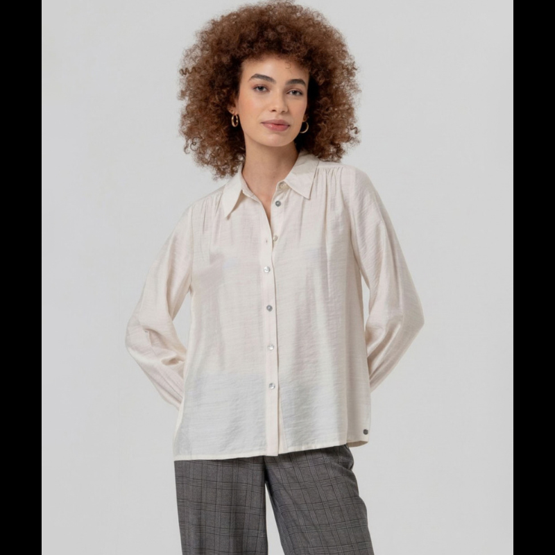 Camisa de manga comprida em crú fluida com gola e botões na frente. Ombros com franzidos que dão volume e punhos bufantes.