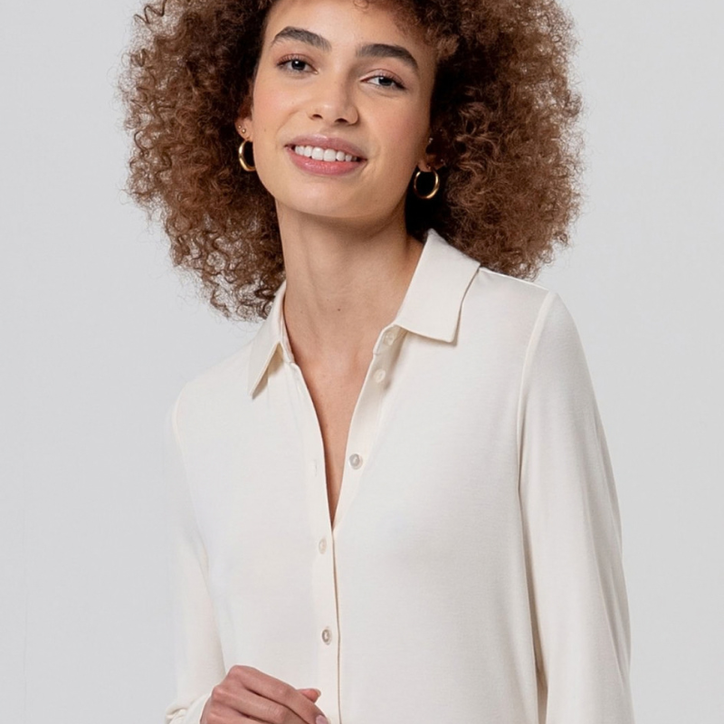 Camisa justa, em crú, em fina viscose de bambu, macia e leve. Gola clássica, fechamento de botão à mesma cor e mangas longas, com uma sensação muito confortável de camisa.