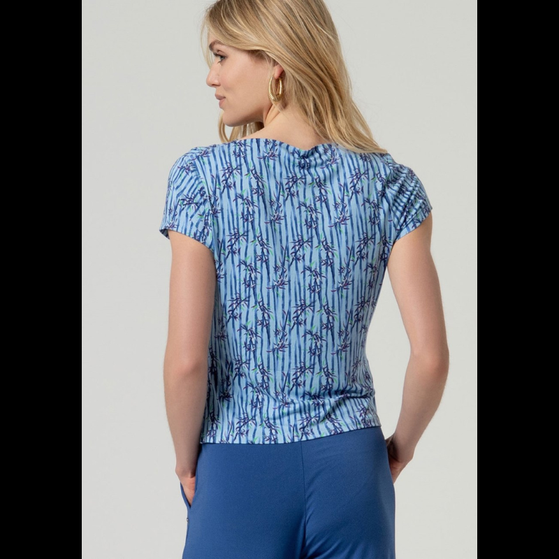 Camisola de manga curta em azul com decote a barco e drapeado elegante num ombro. Apresenta um padrão sofisticado que combina riscas verticais com motivos florais, criando um visual dinâmico e feminino. Confecionada em viscose EcoVero e elastano, oferece conforto e flexibilidade, com a vantagem de ser uma escolha sustentável. Perfeita para looks casuais ou mais elaborados.