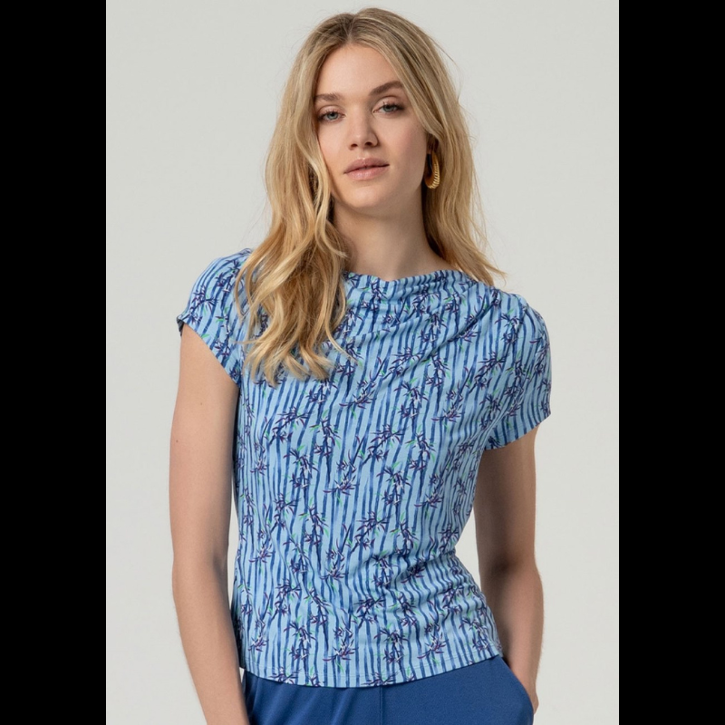 Camisola de manga curta em azul com decote a barco e drapeado elegante num ombro. Apresenta um padrão sofisticado que combina riscas verticais com motivos florais, criando um visual dinâmico e feminino. Confecionada em viscose EcoVero e elastano, oferece conforto e flexibilidade, com a vantagem de ser uma escolha sustentável. Perfeita para looks casuais ou mais elaborados.