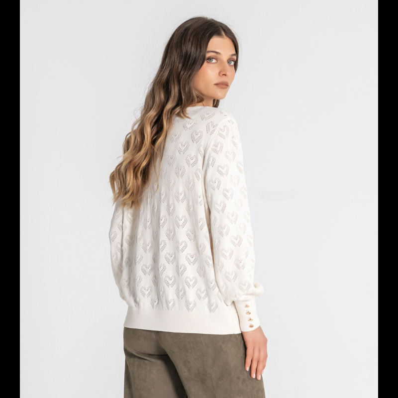 Camisola de malha em crú com decote redondo e detalhes de corações perfurados. As mangas compridas terminam com quatro botões dourados