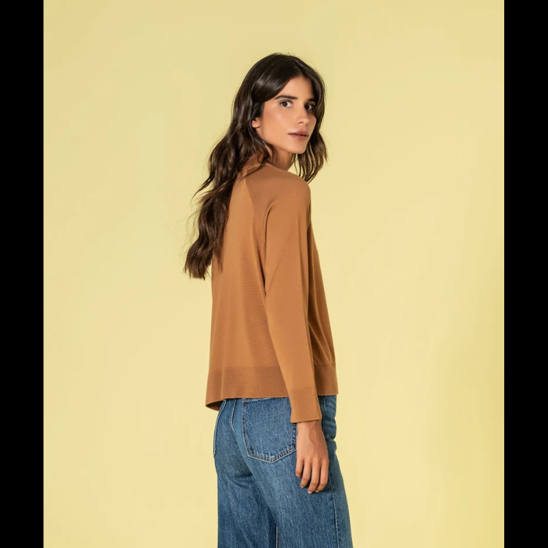 Camisola confecionada em malha fina de qualidade superior, esta camisola combina conforto e refinamento. O decote redondo discreto e o corte solto criam uma silhueta equilibrada e favorecedora. Na tonalidade caramelo, oferece uma alternativa sofisticada ao neutro clássico, mantendo a versatilidade necessária para múltiplas combinações. Uma investimento inteligente para um guarda-roupa atemporal e funcional.