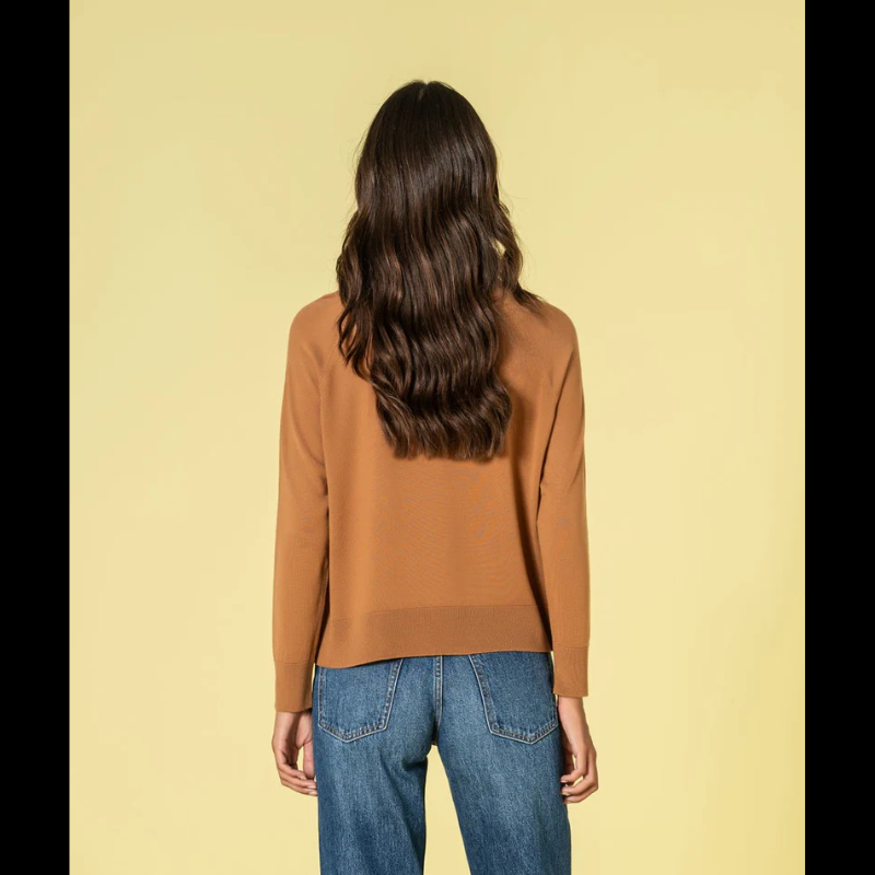 Camisola confecionada em malha fina de qualidade superior, esta camisola combina conforto e refinamento. O decote redondo discreto e o corte solto criam uma silhueta equilibrada e favorecedora. Na tonalidade caramelo, oferece uma alternativa sofisticada ao neutro clássico, mantendo a versatilidade necessária para múltiplas combinações. Uma investimento inteligente para um guarda-roupa atemporal e funcional.