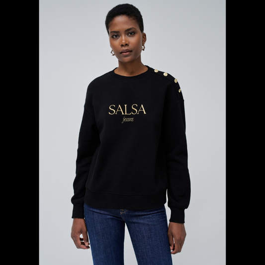 Camisola de felpa em preto com branding em dourado. Camisola de mangas compridas com punhos canelados e decote redondo. Detalhe de quatro botões dourados num ombro.
Corte: Regular fit