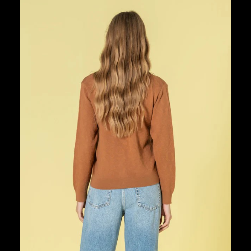 Casaco em tom caramelo com relevo animal print que traz profundidade e dinamismo ao seu estilo. O decote V proporciona uma linha elegante e alongadora, complementado por botões dourados com assinatura de marca que elevam o design. Peça de grande versatilidade, perfeita para composições sofisticadas tanto em contextos casuais como em momentos que exigem maior formalidade.