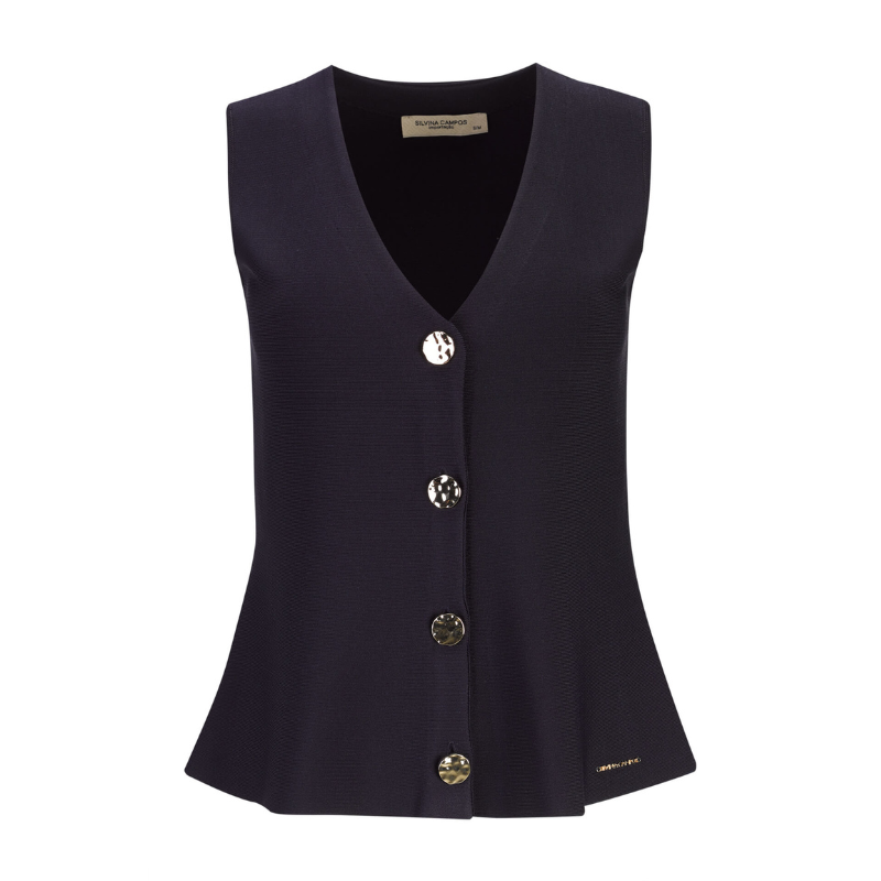 Colete da linha Infinito, muito elegante e versátil que apresenta um corte sofisticado com decote em V e efeito peplum que valoriza a silhueta. O azul marinho transmite confiança e intemporalidade, enquanto os botões dourados adicionam um detalhe refinado e distinto. Combina perfeitamente com branco, pérola, bege, ganga ou cores mais intensas para looks contemporâneos. Ideal tanto para ambientes profissionais como para coordenados descontraídos, mantendo sempre a elegância.