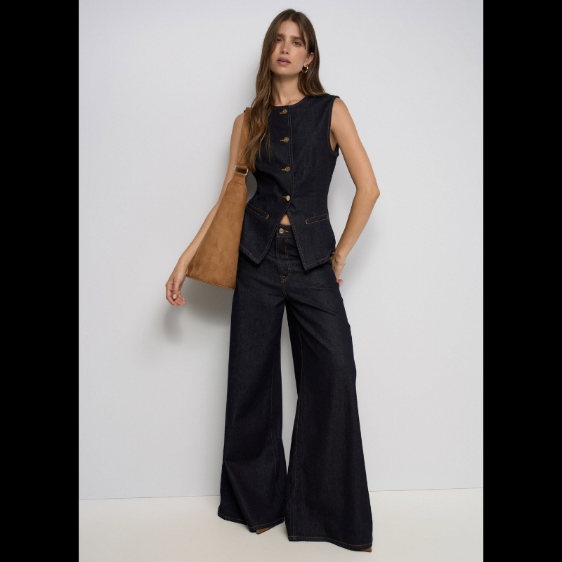Calças jeans super wide leg em denim azul escuro com cintura muito alta. Corte generoso na perna que oferece conforto e estilo contemporâneo. Detalhes funcionais incluem abertura frontal com fecho e botão, cinco bolsos espaçosos e presilhas