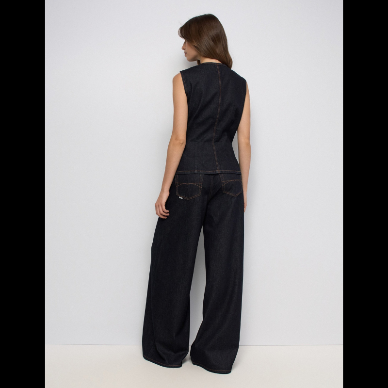 Calças jeans super wide leg em denim azul escuro com cintura muito alta. Corte generoso na perna que oferece conforto e estilo contemporâneo. Detalhes funcionais incluem abertura frontal com fecho e botão, cinco bolsos espaçosos e presilhas