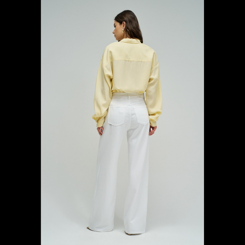 Calças jeans wide leg em branco puro que combinam estilo e conforto. O corte amplo na perna oferece liberdade de movimento e um visual moderno e descontraído. Equipadas com cinco bolsos funcionais, fecho de correr e botão na cintura para um ajuste seguro, além de presilhas para cinto. Peça versátil que funciona tanto em looks casuais como em composições mais sofisticadas.